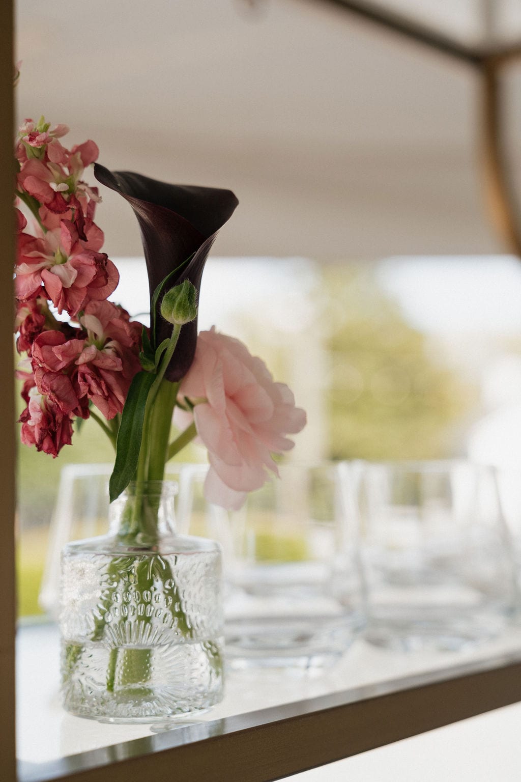 Bud vase with burgundy calla, stock, and pink ranunculus at the Callie & Jeremy wedding — designed by Lael Florals