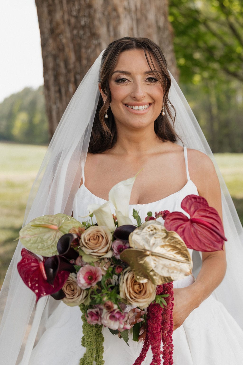 Bride holding an anthurium, gold-leaf, and toffee rose bouquet at the Callie & Jeremy wedding — designed by Lael Florals