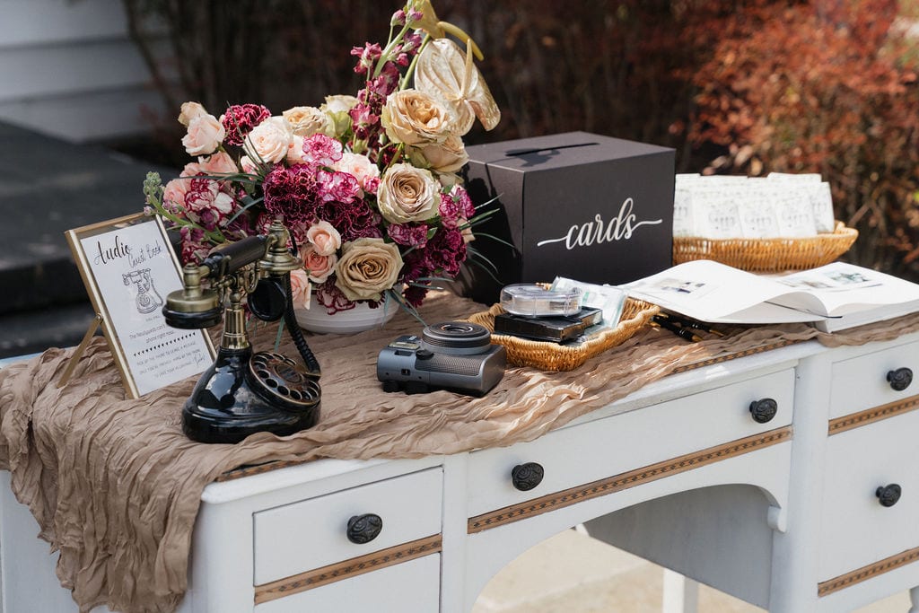 Guest book desk with a burgundy and toffee rose arrangement at the Callie & Jeremy wedding — designed by Lael Florals