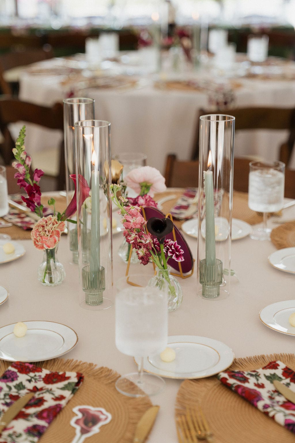 Guest table with bud vases of snapdragons and callas and sage taper candles at the Callie & Jeremy wedding — designed by Lael Florals