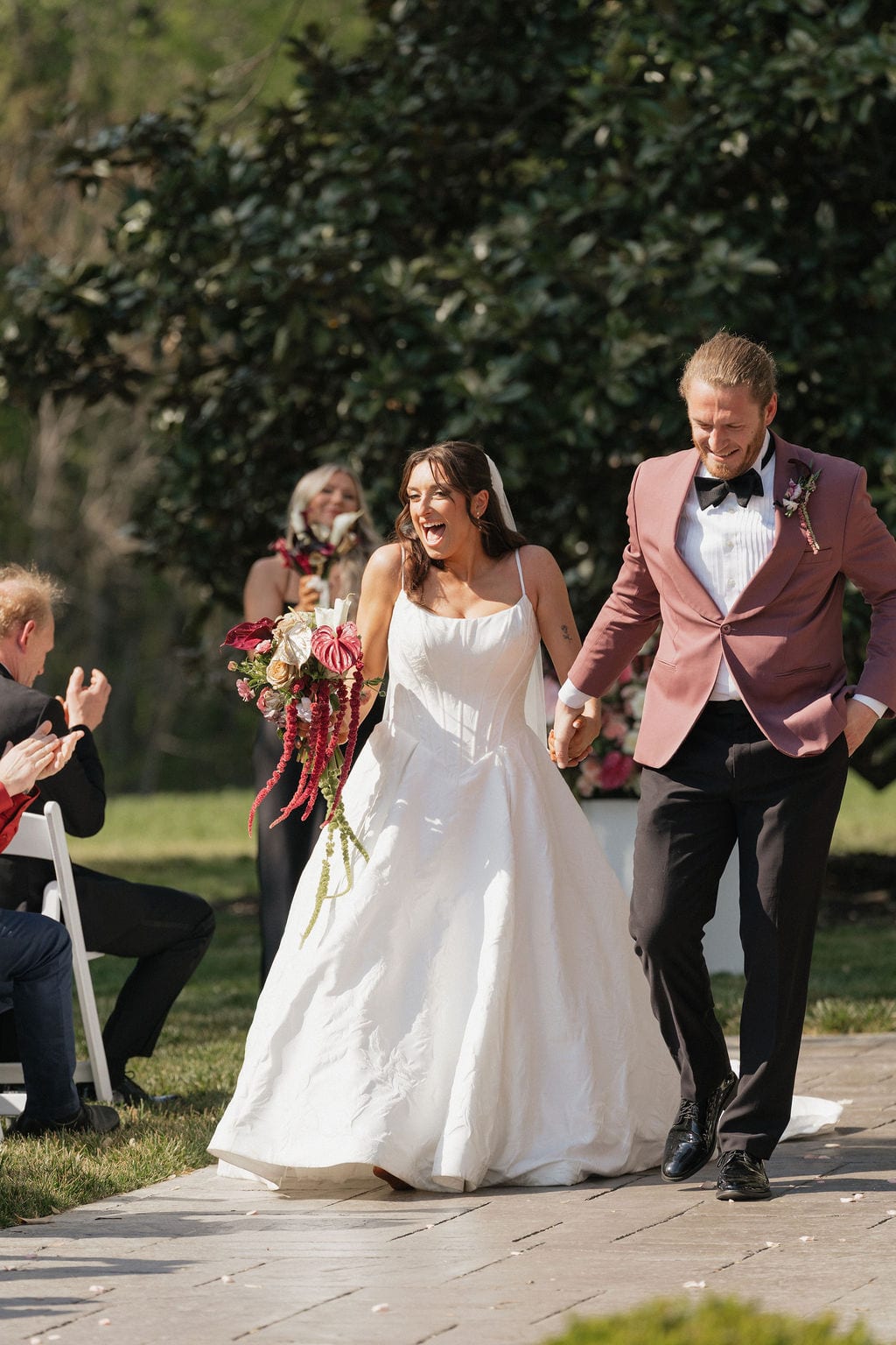 Bride carrying a cascading burgundy anthurium bouquet up the aisle at the Callie & Jeremy wedding — designed by Lael Florals