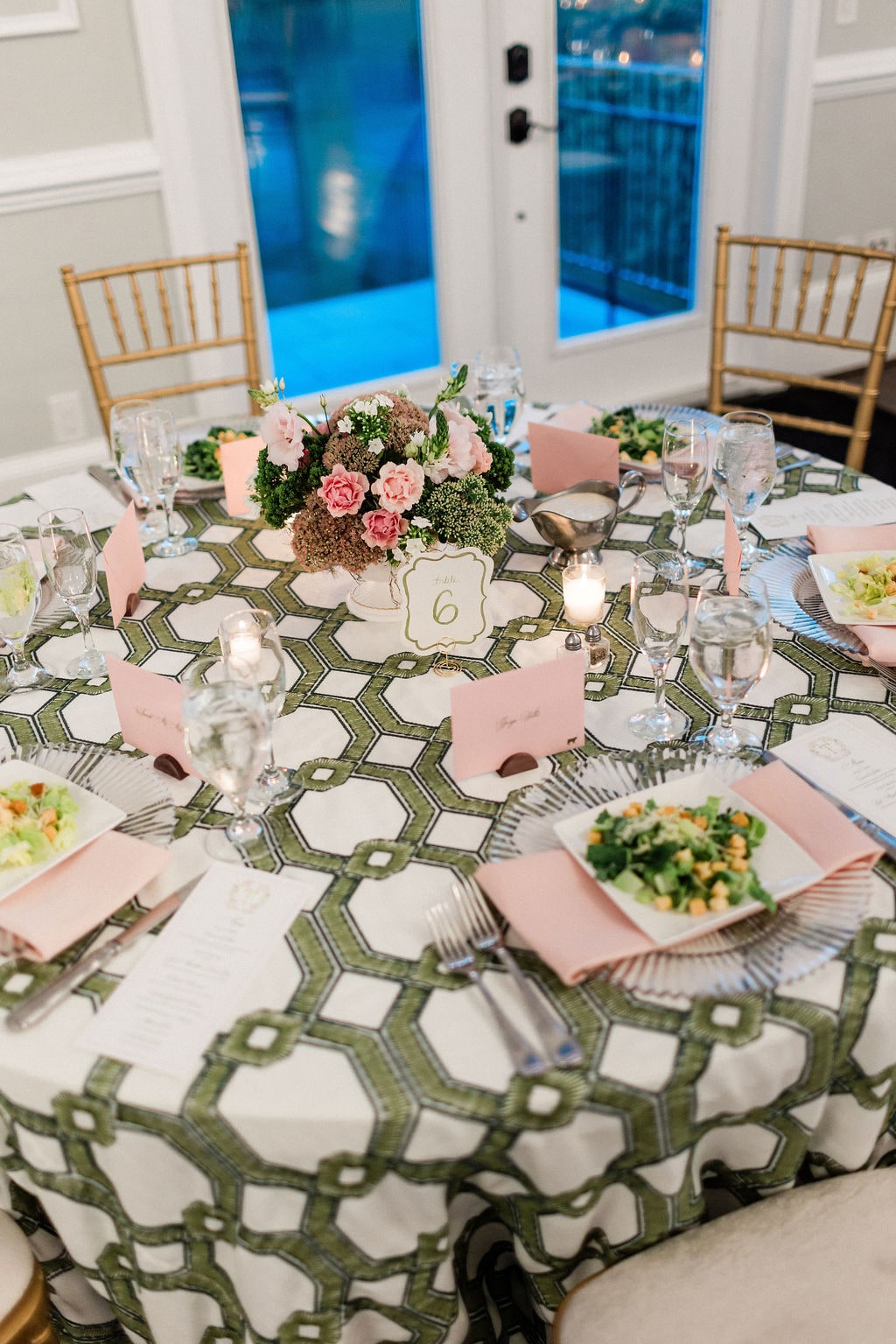 A guest table from above with a compact pink and green centerpiece on patterned linen at the Emily & Thomas wedding — designed by Lael Florals