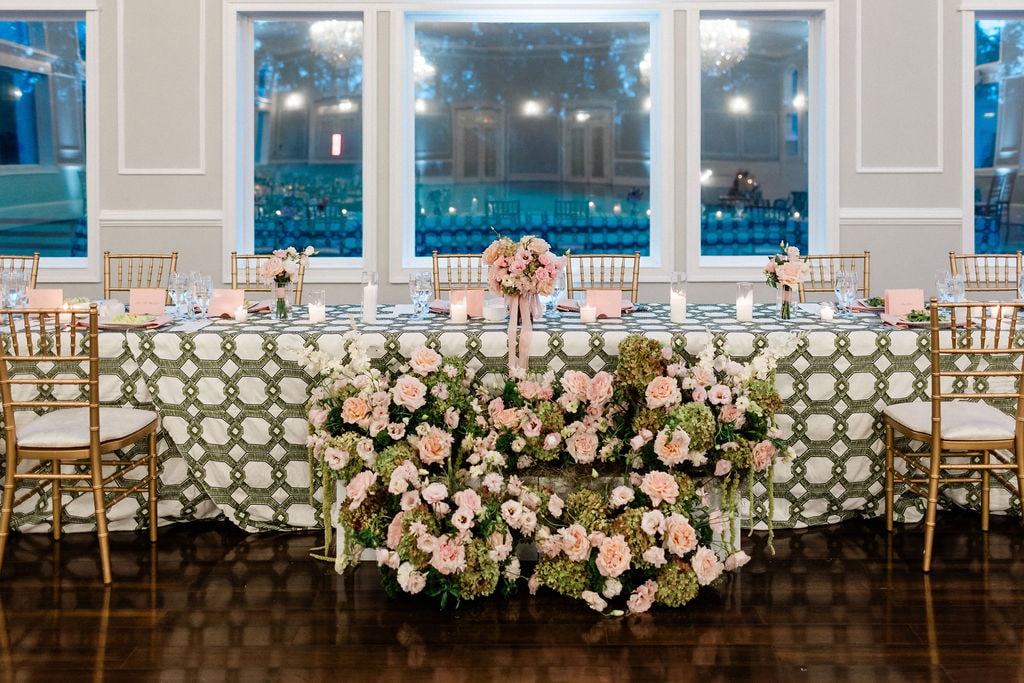 The head table with a blush and green floral meadow running along its front at the Emily & Thomas wedding — designed by Lael Florals