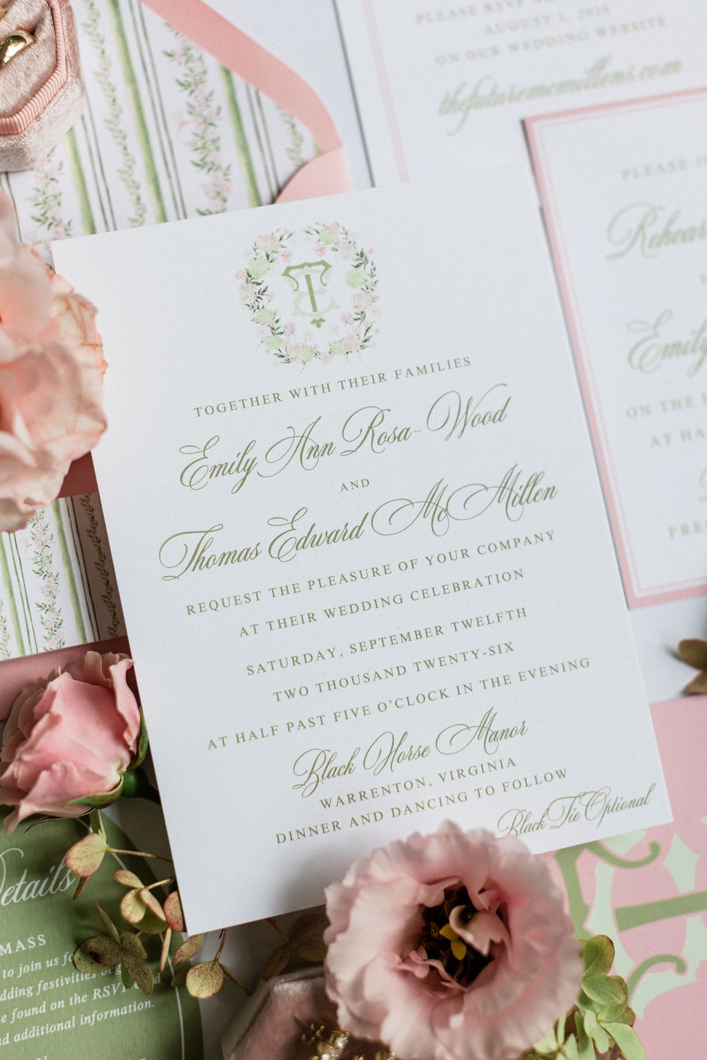The invitation suite with blush roses, a peony and greenery tucked around the card at the Emily & Thomas wedding — designed by Lael Florals