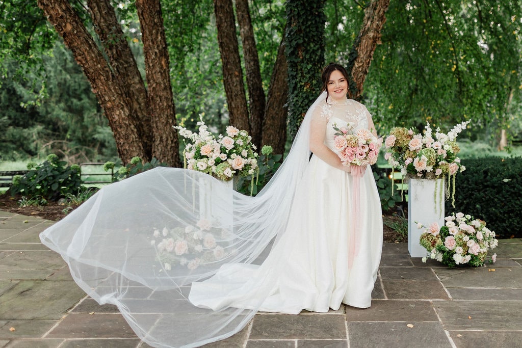 The veil tossed in front of the ceremony pedestal arrangements at the Emily & Thomas wedding — designed by Lael Florals