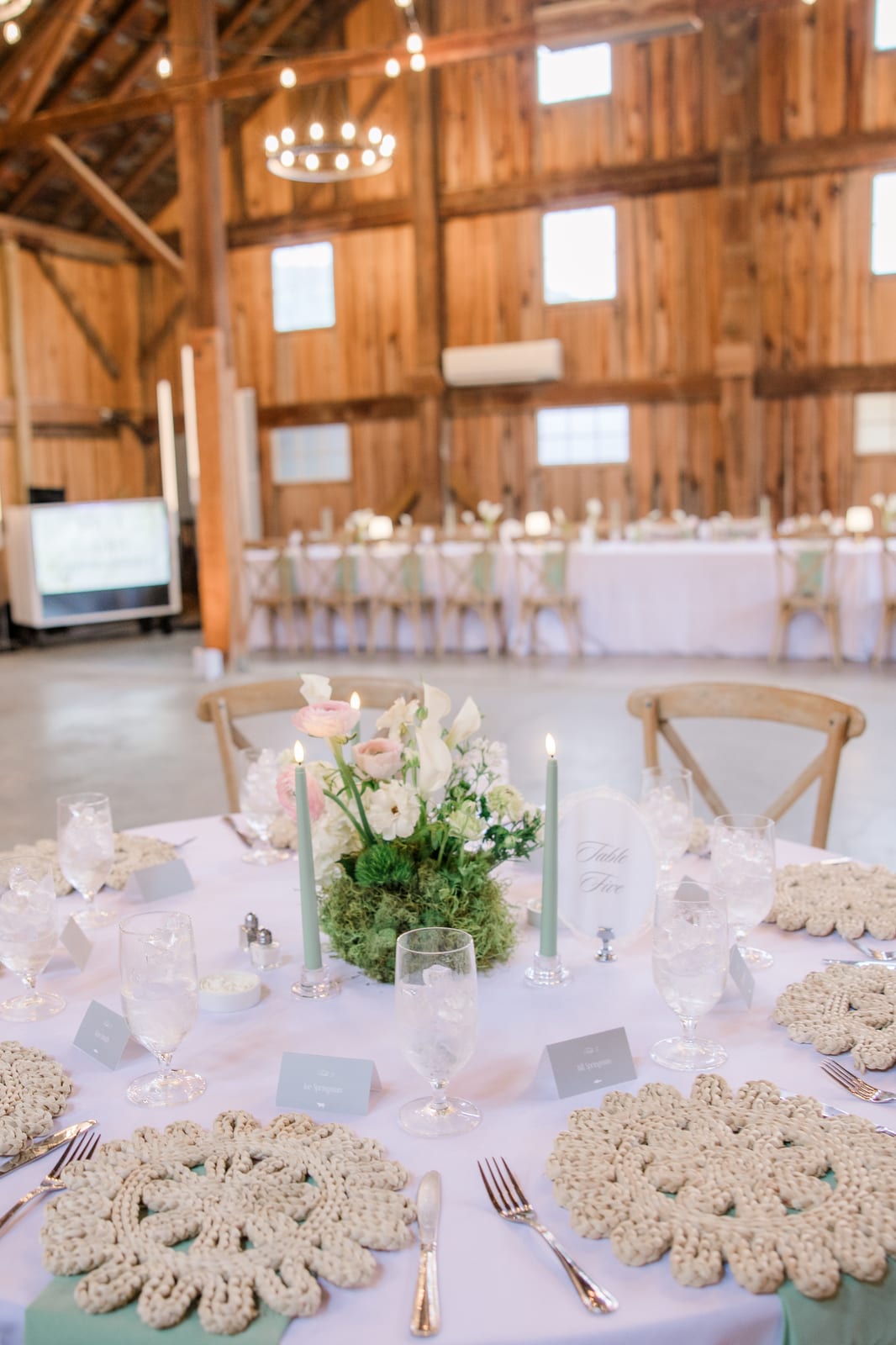 Barn reception tablescape with moss centerpiece and sage tapers at the Gabby & Matt wedding — designed by Lael Florals