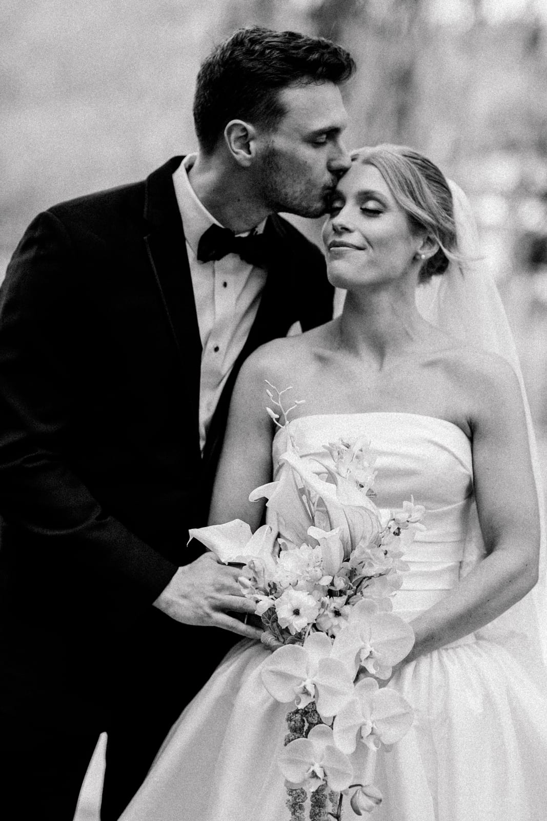 Black and white portrait of the couple with the orchid cascade bouquet at the Gabby & Matt wedding — designed by Lael Florals