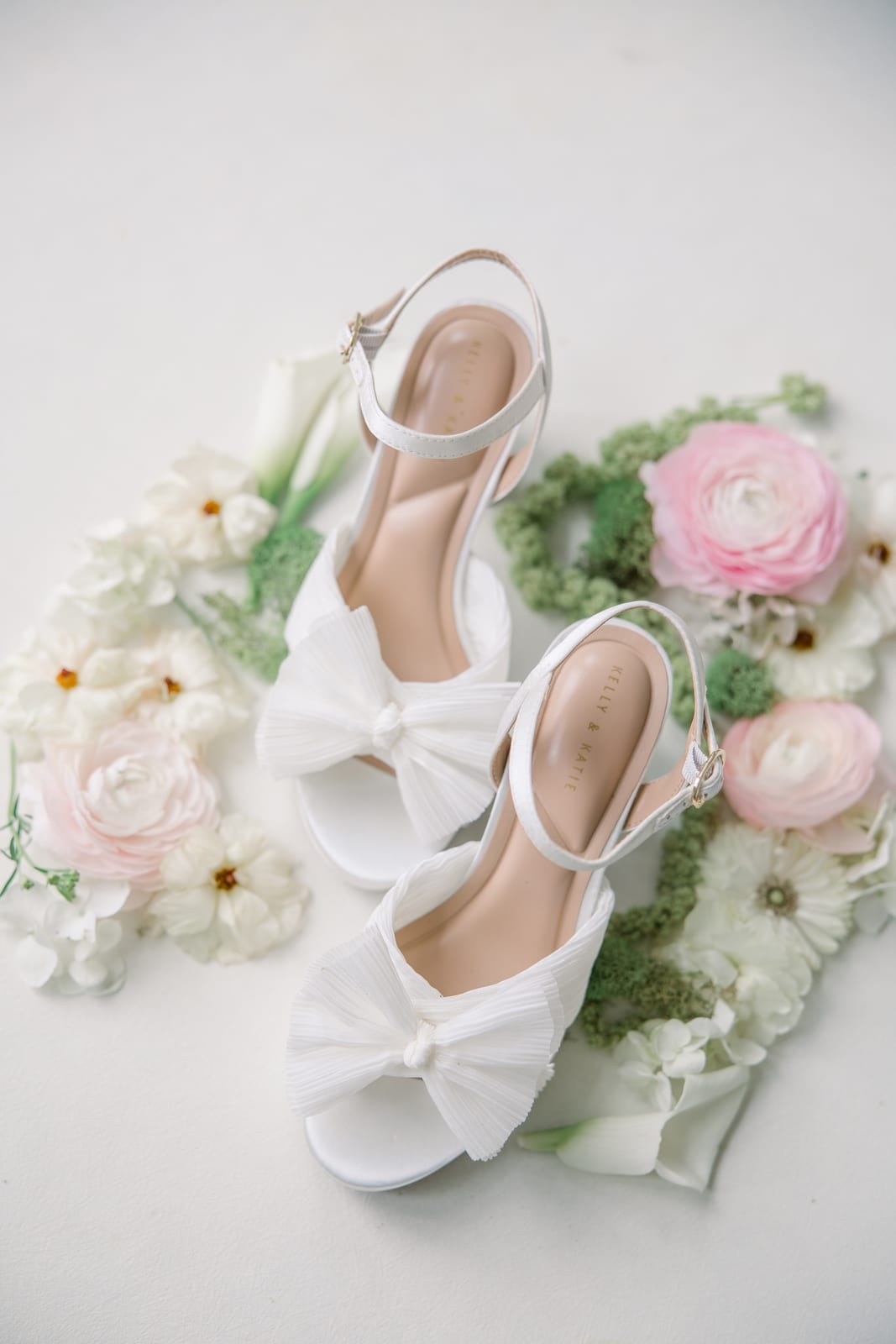 Bridal heels styled with blush ranunculus, callas, and greenery at the Gabby & Matt wedding — designed by Lael Florals