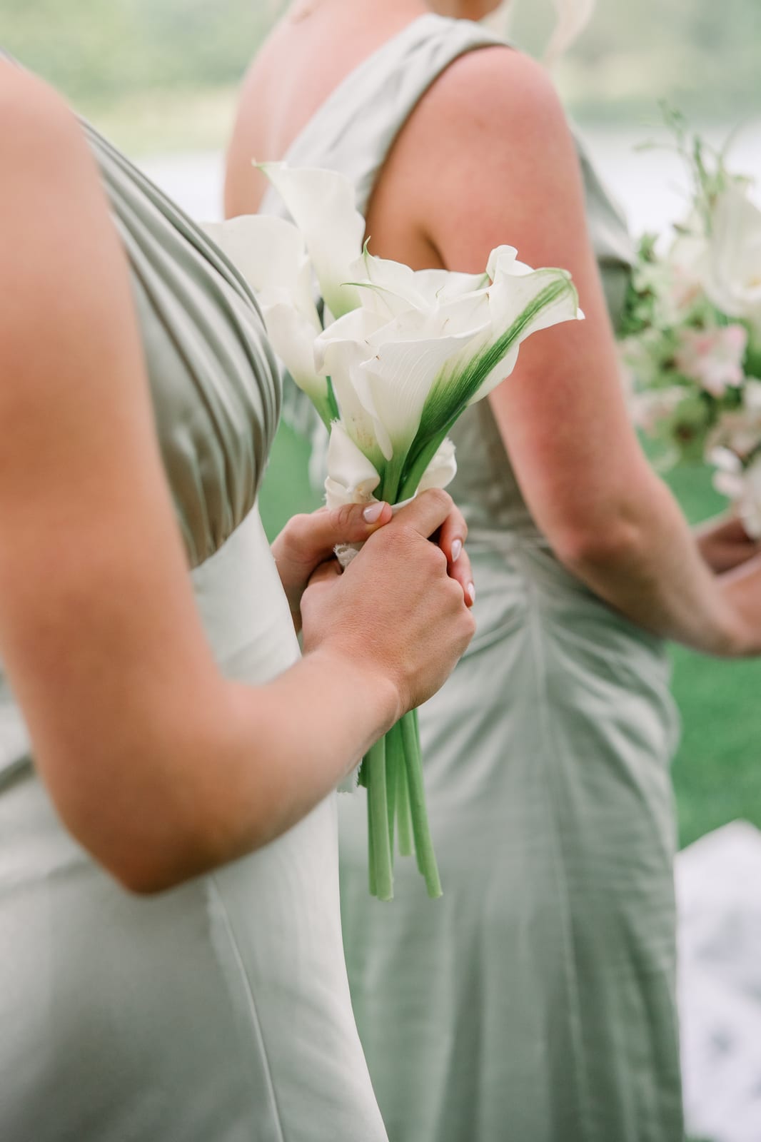 Bridesmaid's white calla lily bouquet against a sage silk gown at the Gabby & Matt wedding — designed by Lael Florals