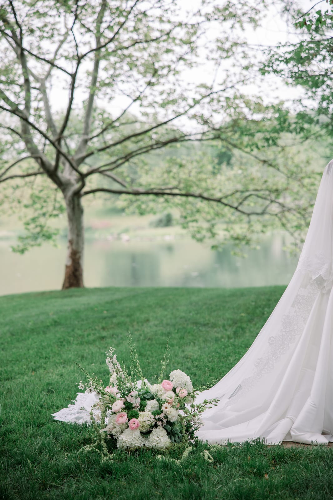 Blush ranunculus and hydrangea ceremony piece beside the bride's train at the Gabby & Matt wedding — designed by Lael Florals