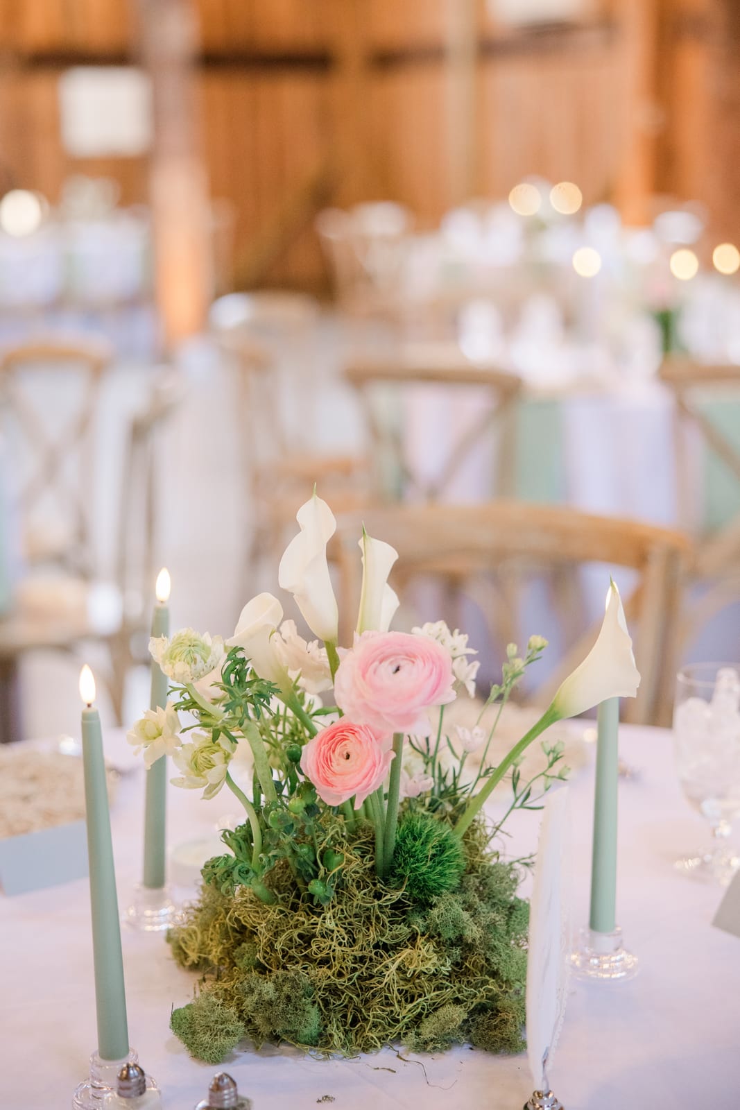 Ranunculus and calla lily moss centerpiece in the barn at the Gabby & Matt wedding — designed by Lael Florals
