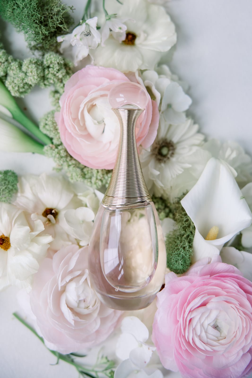 Perfume bottle nestled in blush ranunculus and white callas at the Gabby & Matt wedding — designed by Lael Florals