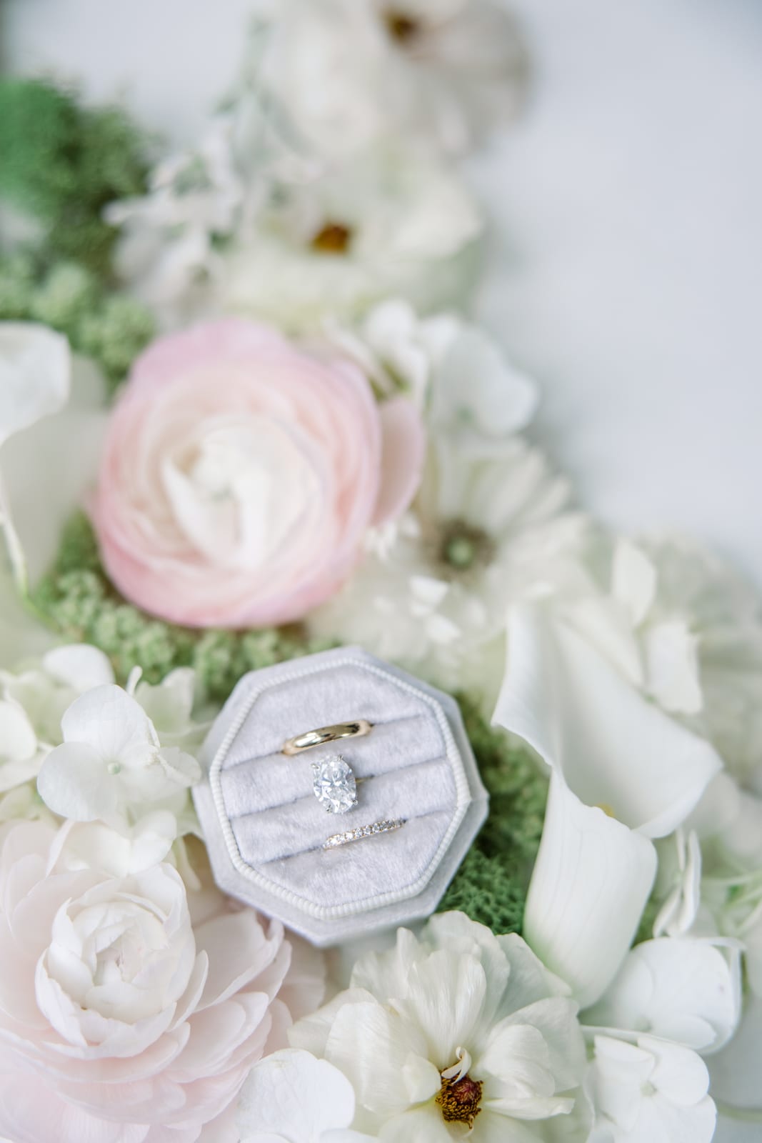 Wedding rings in a velvet box atop blush ranunculus and white blooms at the Gabby & Matt wedding — designed by Lael Florals