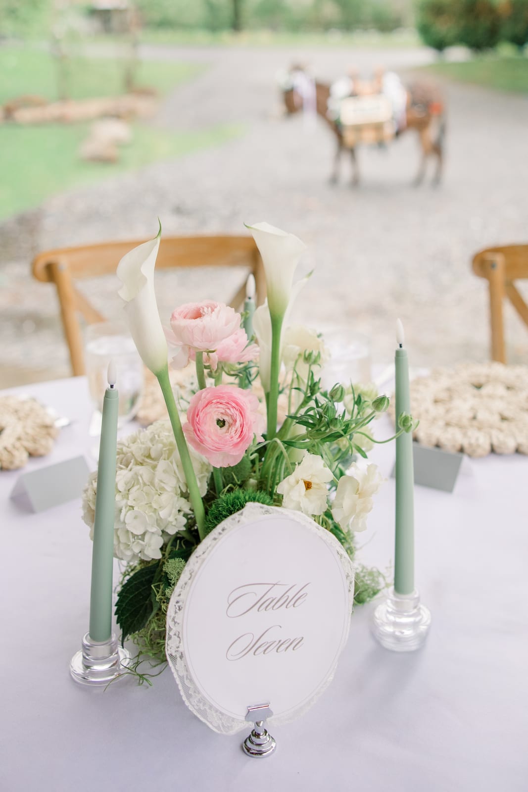 Table Seven calla and ranunculus centerpiece under the tent at the Gabby & Matt wedding — designed by Lael Florals