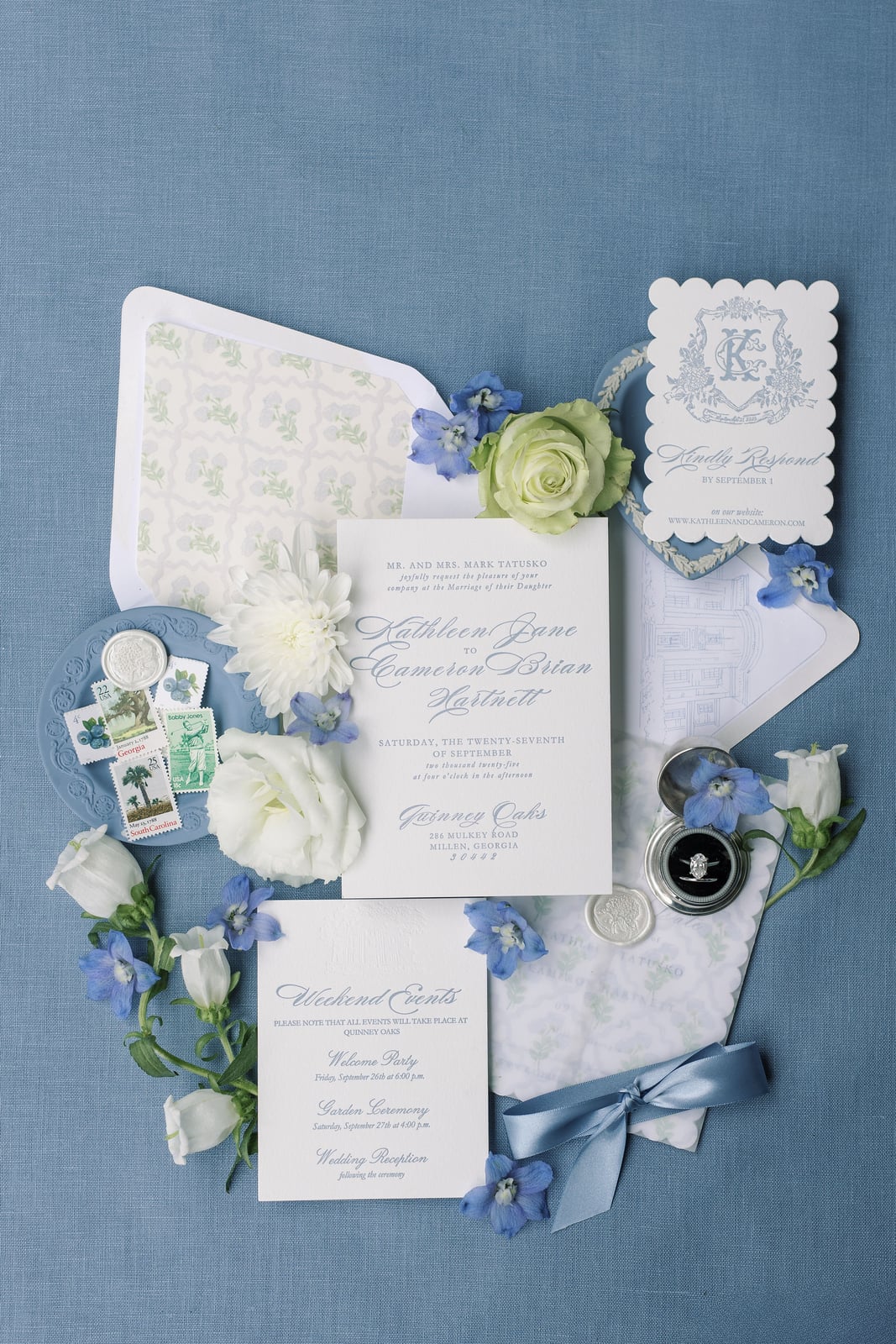 The wedding's invitation suite styled on french blue linen — calligraphed invitation, wax-sealed vellum, blue ribbon, stamps, white roses and blue delphinium — from the Hartnett wedding