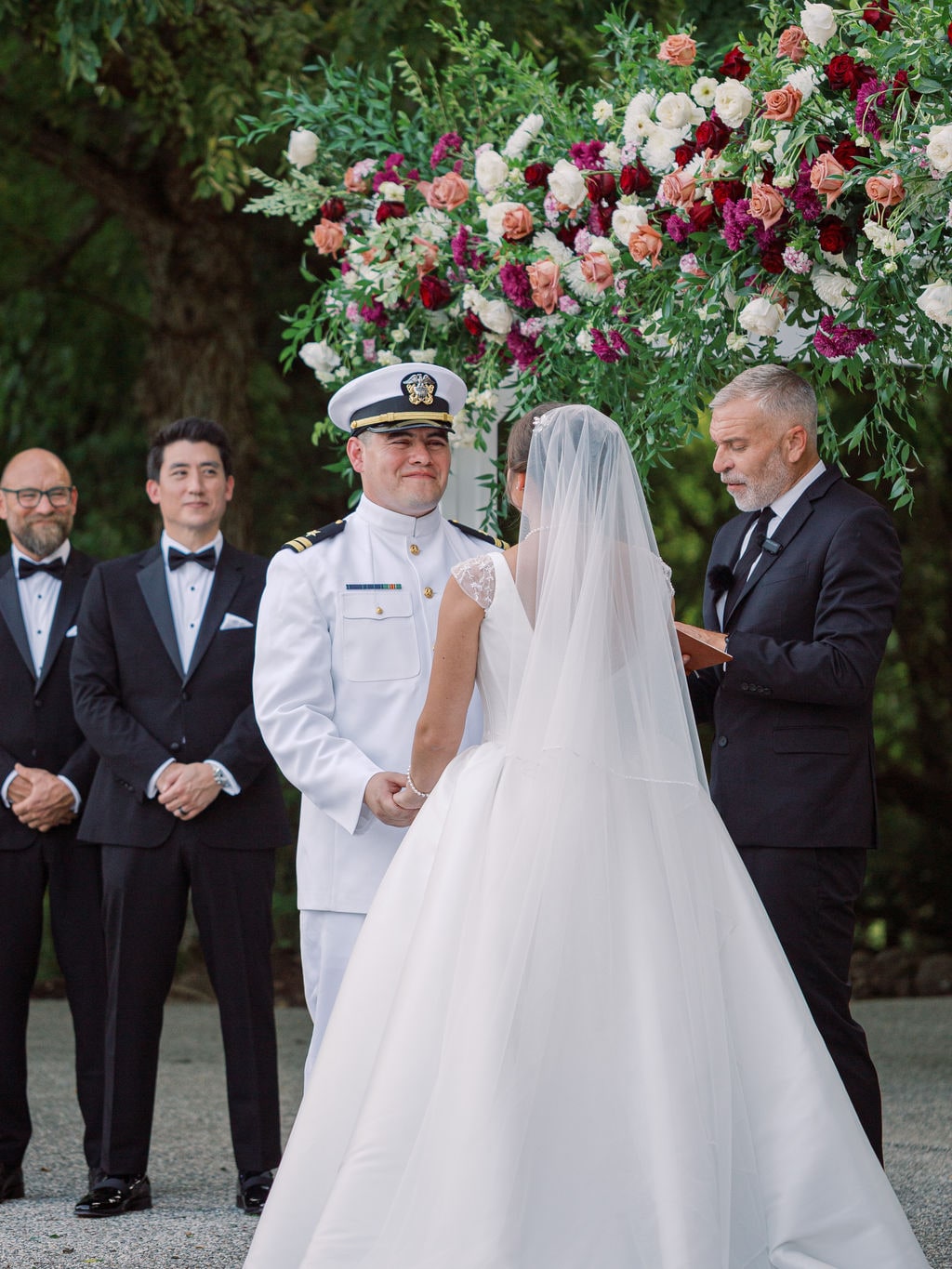 Burgundy, peach and cream garden roses clustered at the pergola corner during the vows at the Karlie & Hank wedding — designed by Lael Florals