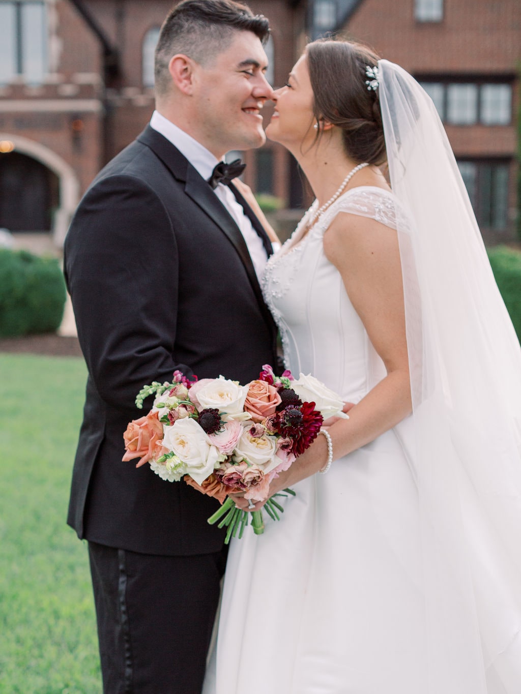 The bridal bouquet held between the couple on the lawn at the Karlie & Hank wedding — designed by Lael Florals