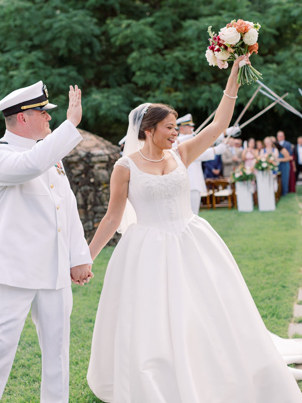 The bridal bouquet lifted overhead with its ribbons trailing at the Karlie & Hank wedding — designed by Lael Florals