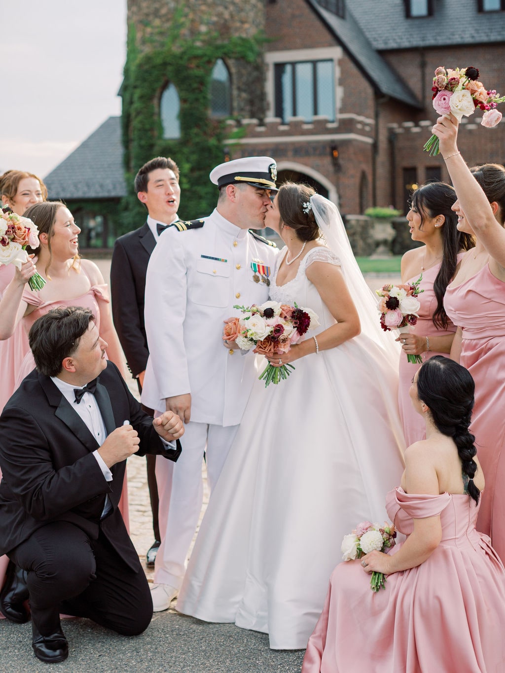 Bridesmaid bouquets lifted over the couple as they kiss at the Karlie & Hank wedding — designed by Lael Florals