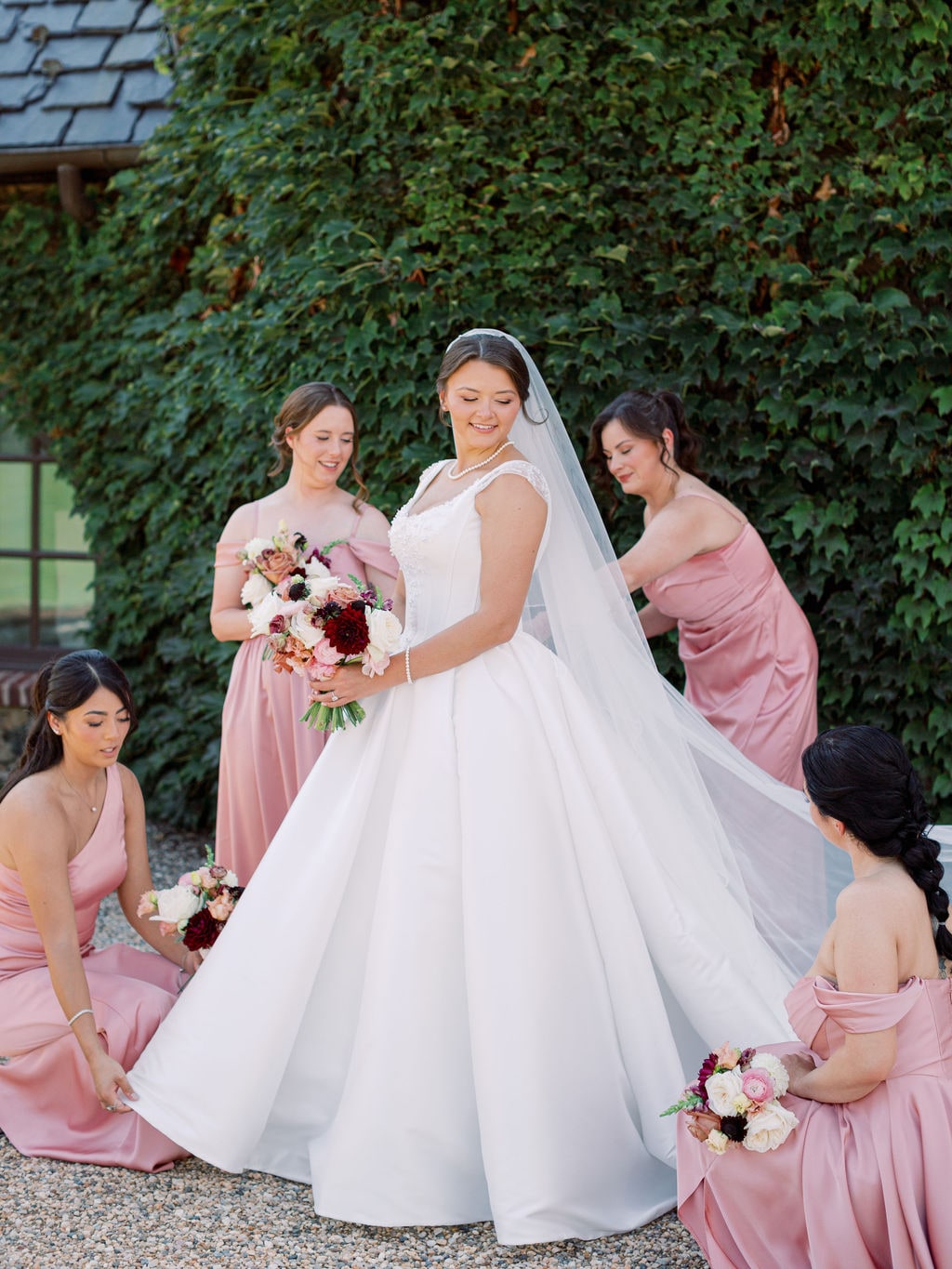 The bridal bouquet and four bridesmaid bouquets against the ivy wall at the Karlie & Hank wedding — designed by Lael Florals