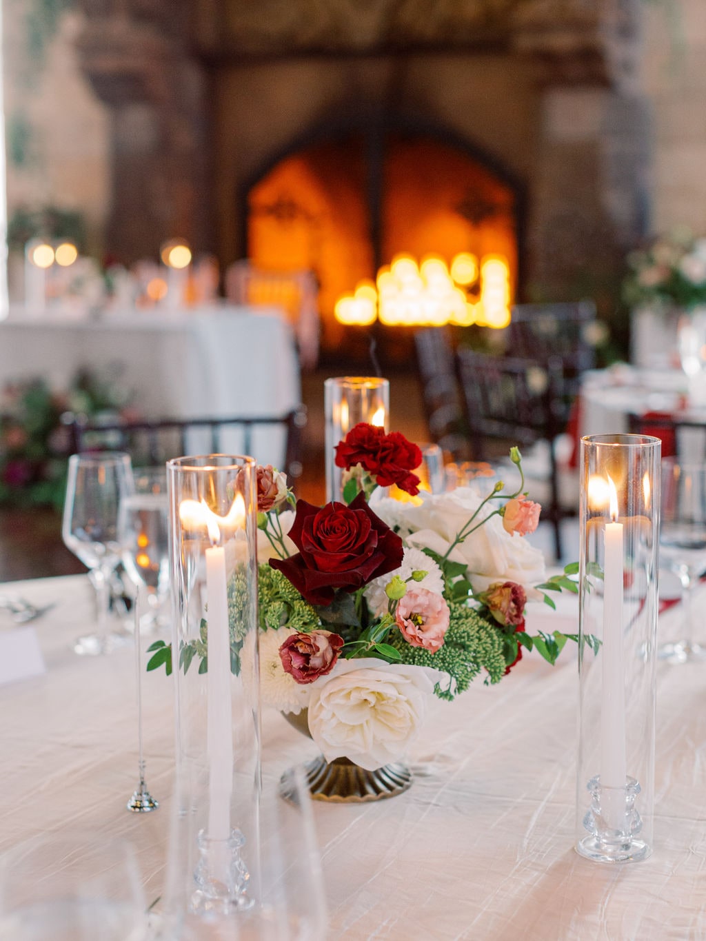 A compote centerpiece among hurricane tapers in firelight at the Karlie & Hank wedding — designed by Lael Florals