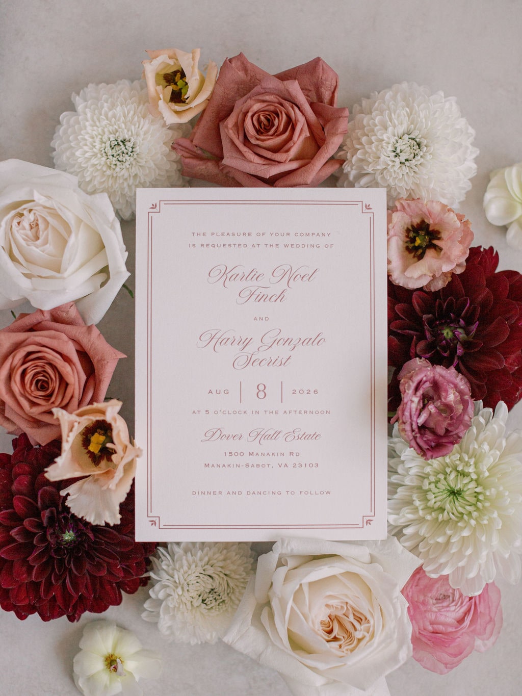 The wedding's invitation suite ringed by a wreath of terracotta roses, cream garden roses, burgundy dahlias, white mums and lisianthus — from the Karlie & Hank wedding at Dover Hall