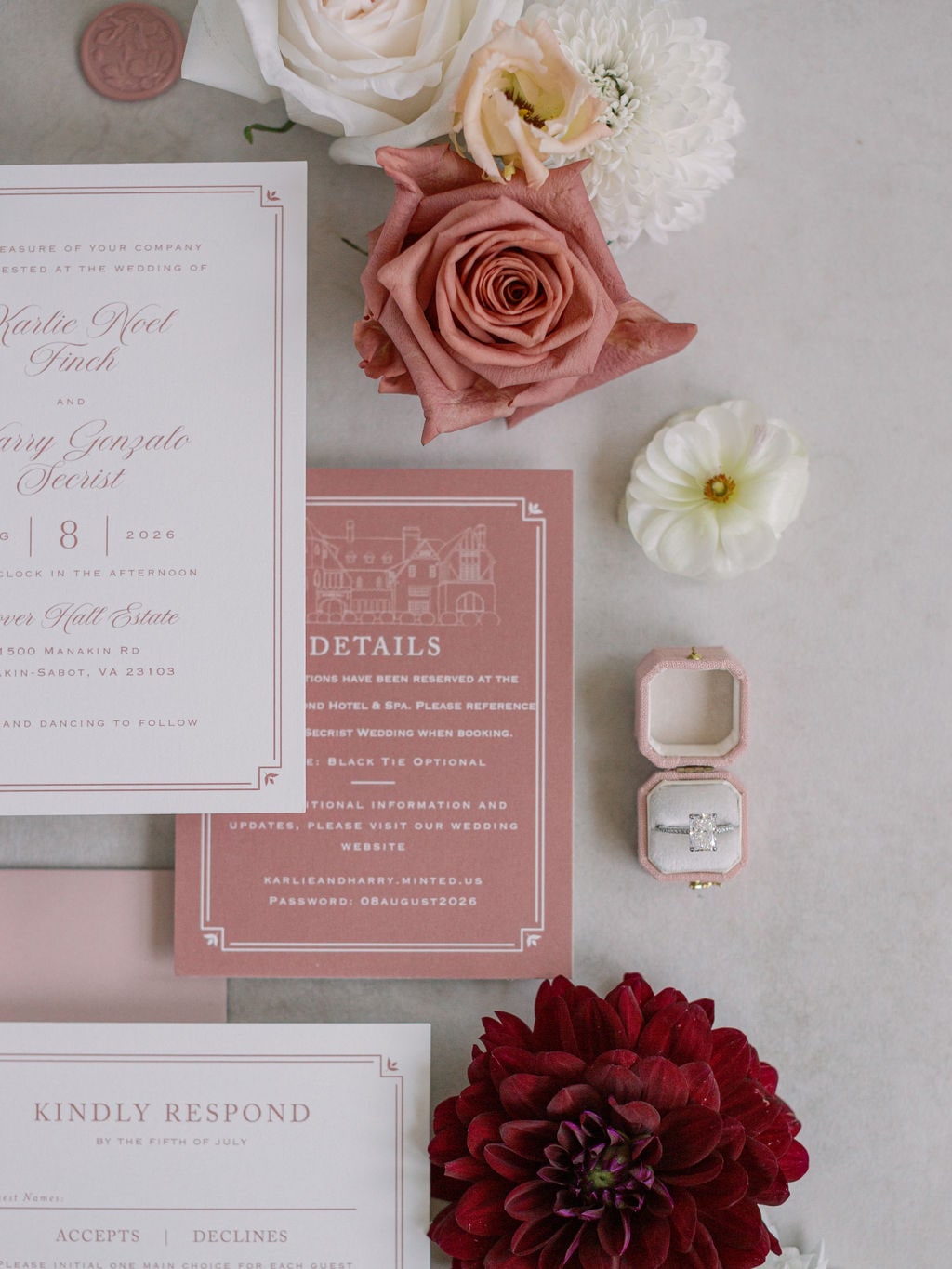 The invitation suite on grey stone with an oversized terracotta rose, cream ranunculus and a burgundy dahlia at the Karlie & Hank wedding — designed by Lael Florals