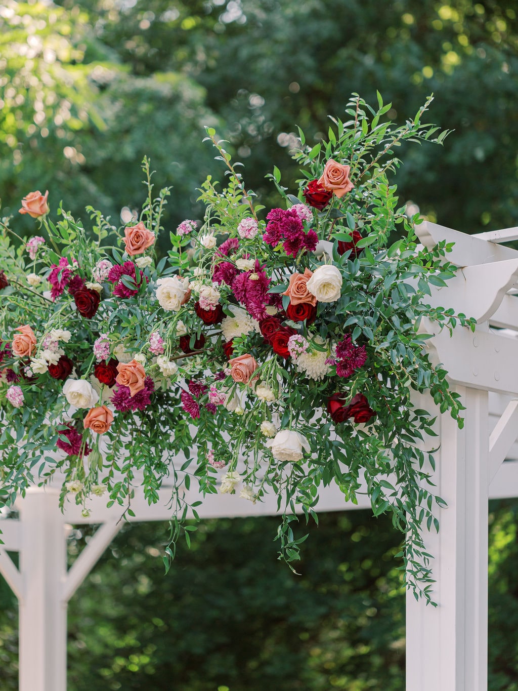 Corner cascade of the pergola install in terracotta roses and burgundy dahlias at the Karlie & Hank wedding — designed by Lael Florals