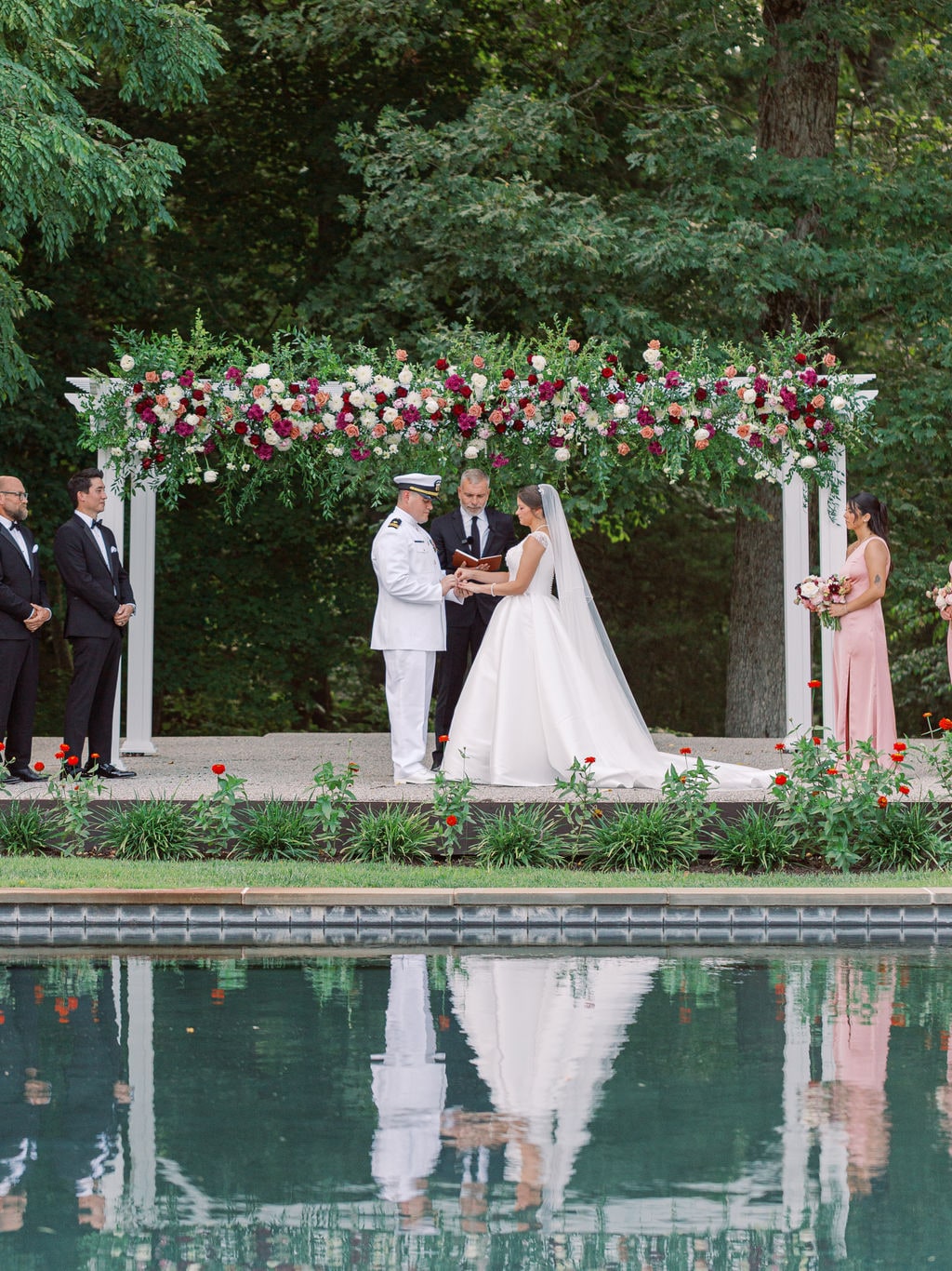 The pergola garland end to end with its reflection in the water at the Karlie & Hank wedding — designed by Lael Florals