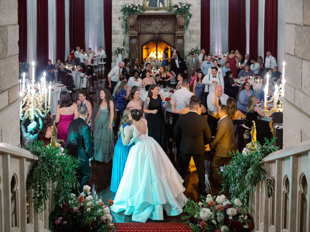 The reception room from the top of the stair, balustrade arrangements in the foreground, at the Karlie & Hank wedding — designed by Lael Florals