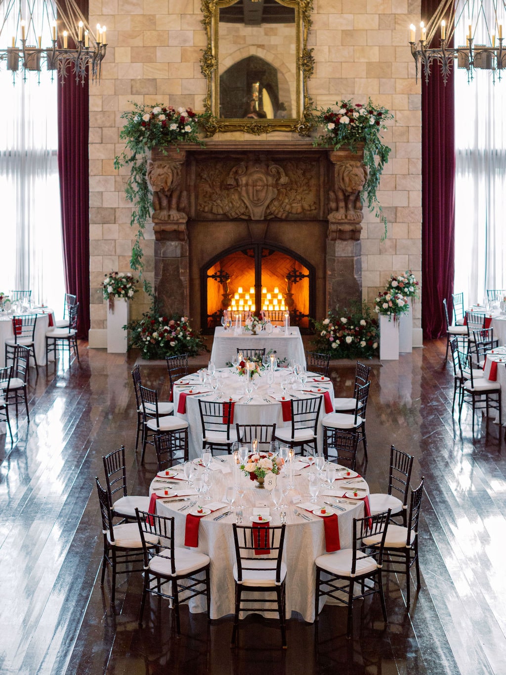 The reception set with mantel garland, head table and round centerpieces at the Karlie & Hank wedding — designed by Lael Florals