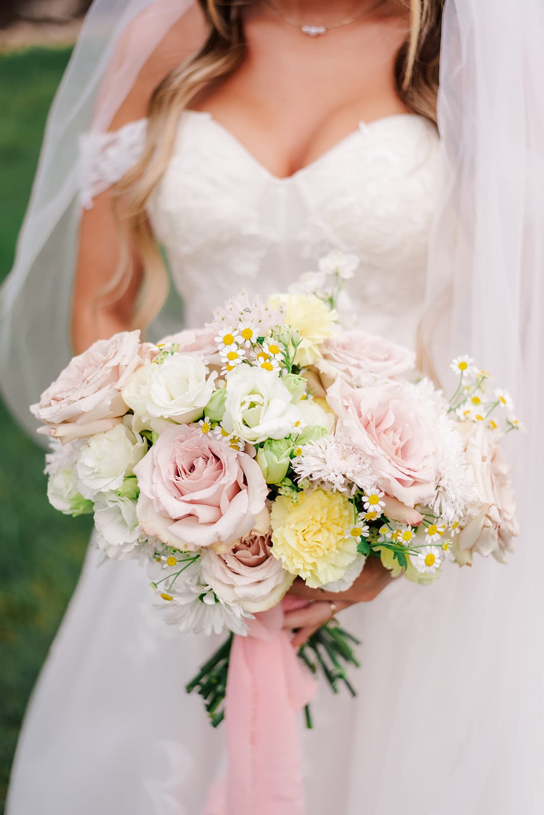 A loose, garden-gathered bridal bouquet of blush roses, chamomile, and yellow carnations — designed by Lael Florals