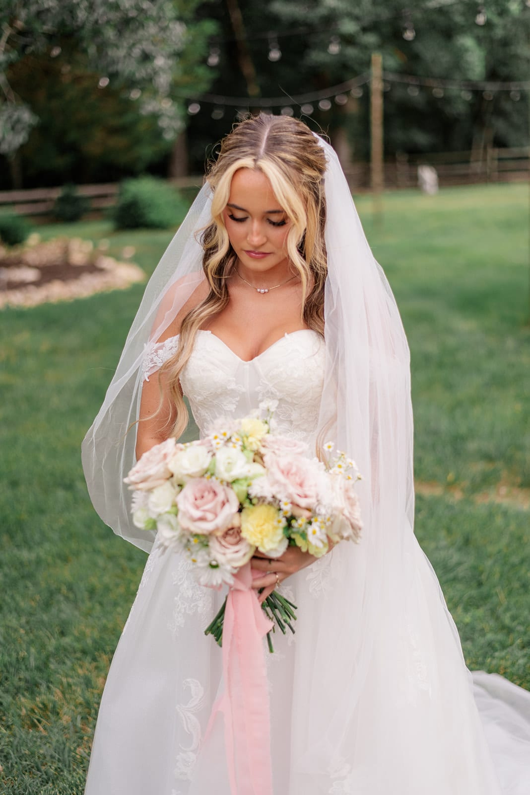 Bride gazing down at her blush rose and chamomile bouquet — designed by Lael Florals
