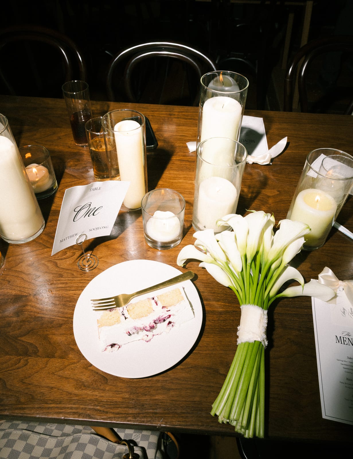 Calla lily bouquet beside cake and pillar candles at the Sharon & Matt wedding — designed by Lael Florals