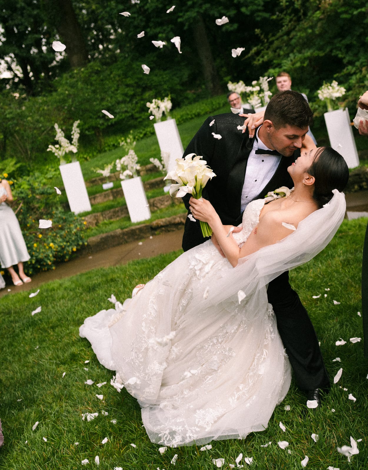Bride raising her white calla bouquet in a shower of petals at the Sharon & Matt wedding — designed by Lael Florals