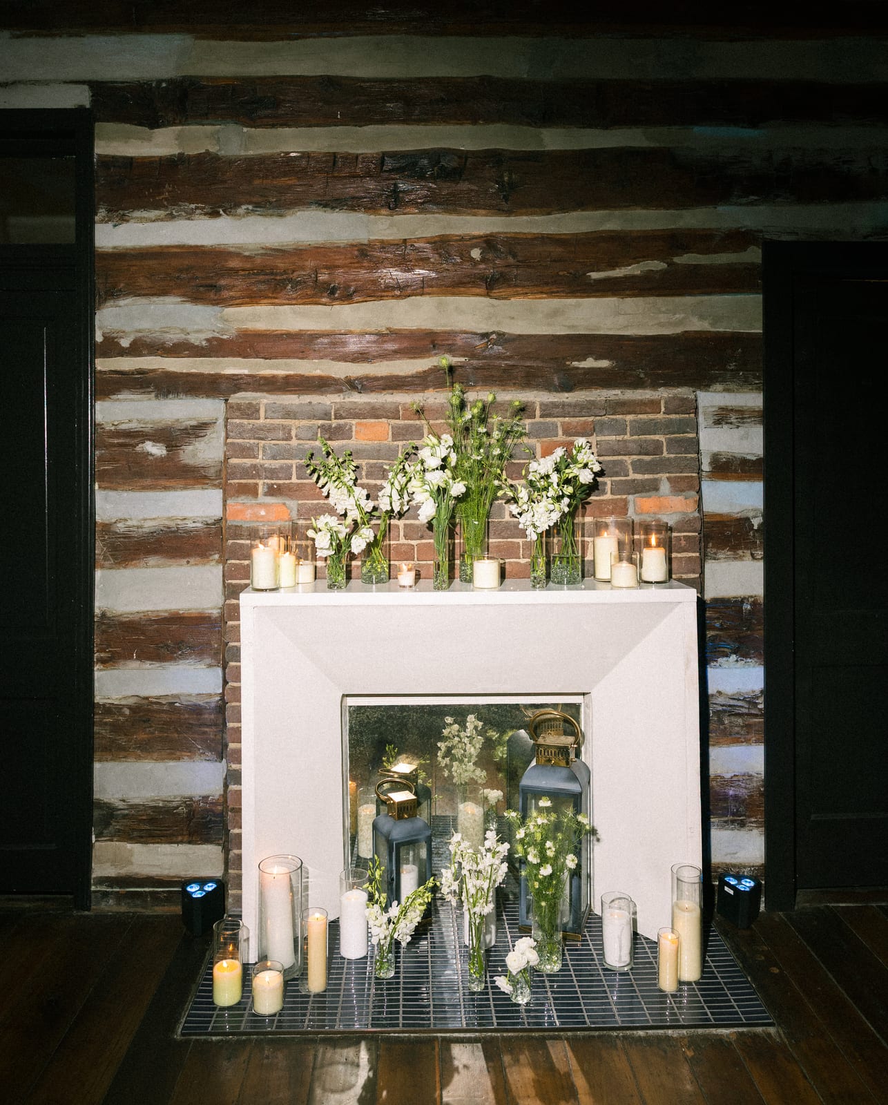 Fireplace styled with white stems, lanterns, and candles at the Sharon & Matt wedding — designed by Lael Florals