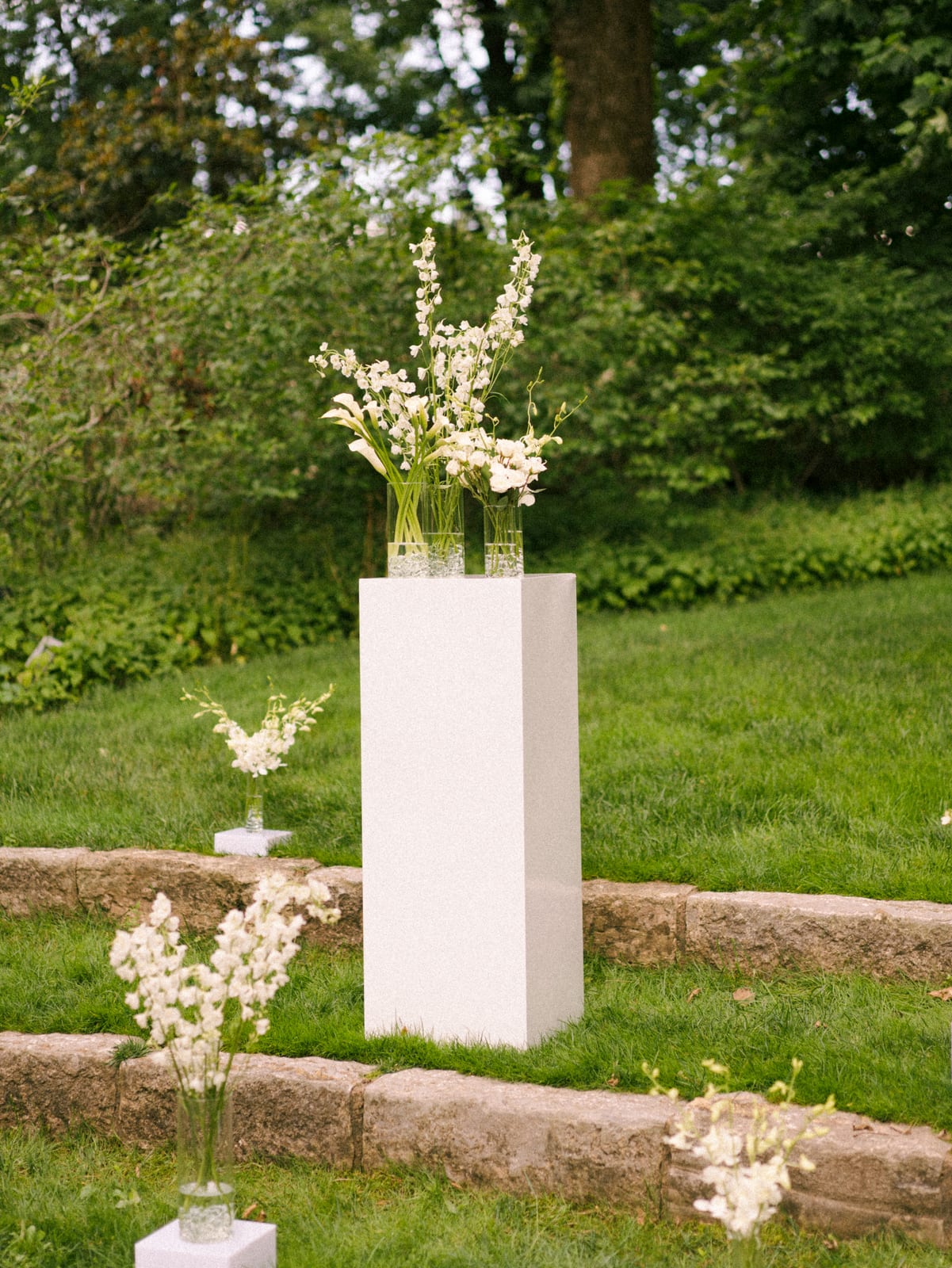 Calla and delphinium vases on a white garden pedestal at the Sharon & Matt wedding — designed by Lael Florals