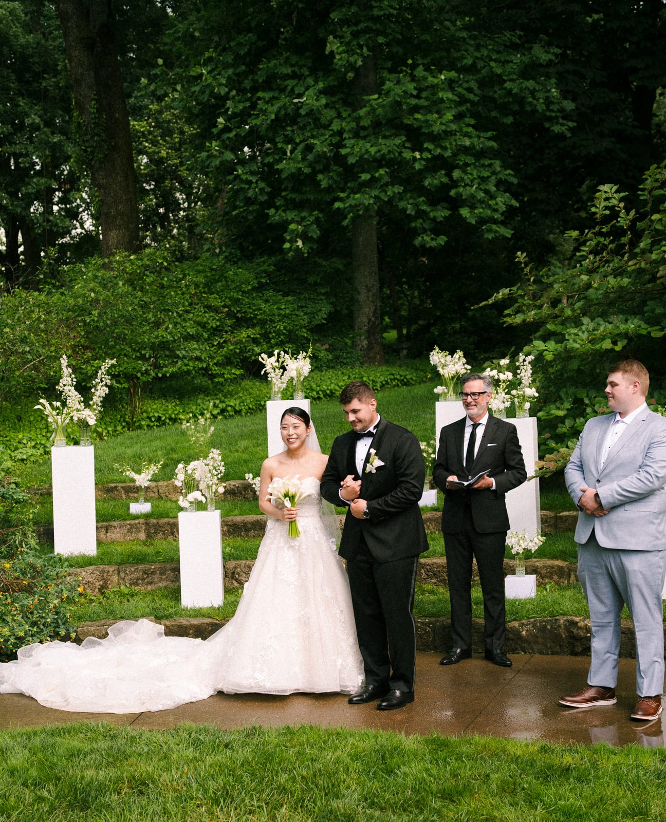 Newlyweds smiling with calla bouquet before the pedestal floral installation at the Sharon & Matt wedding — designed by Lael Florals