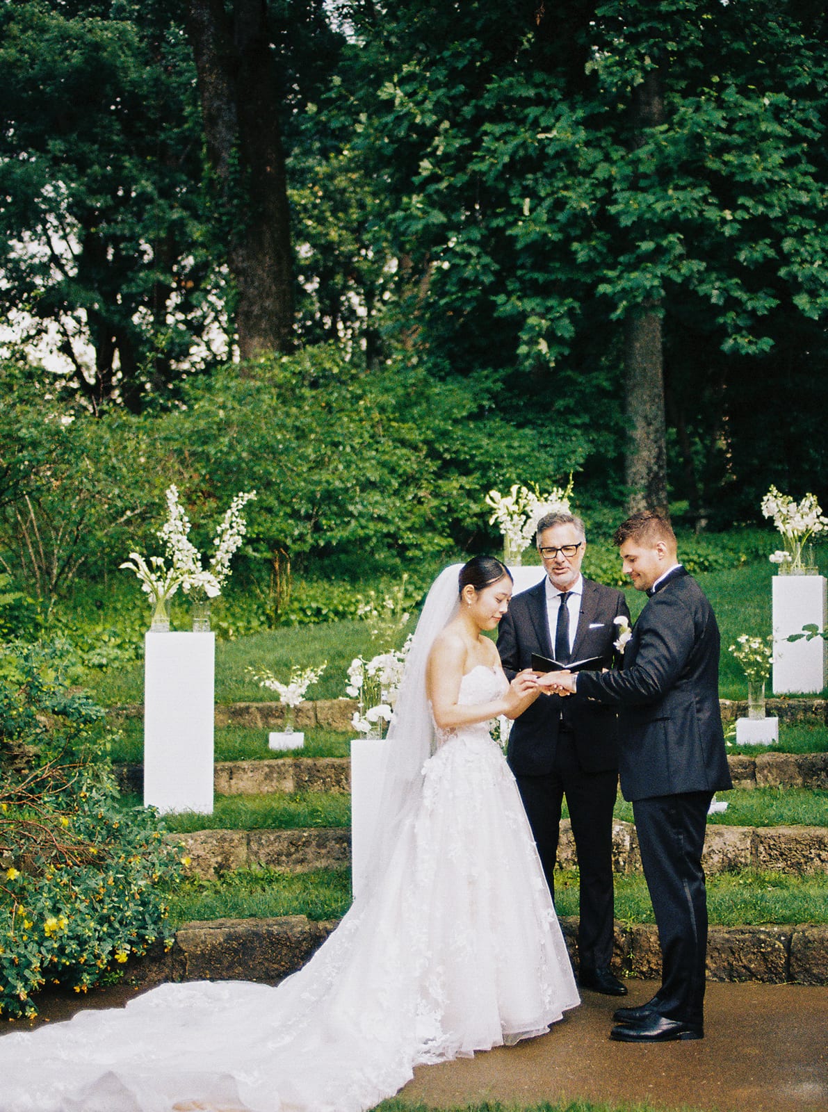 Ring exchange framed by white pedestal florals at the Sharon & Matt wedding — designed by Lael Florals
