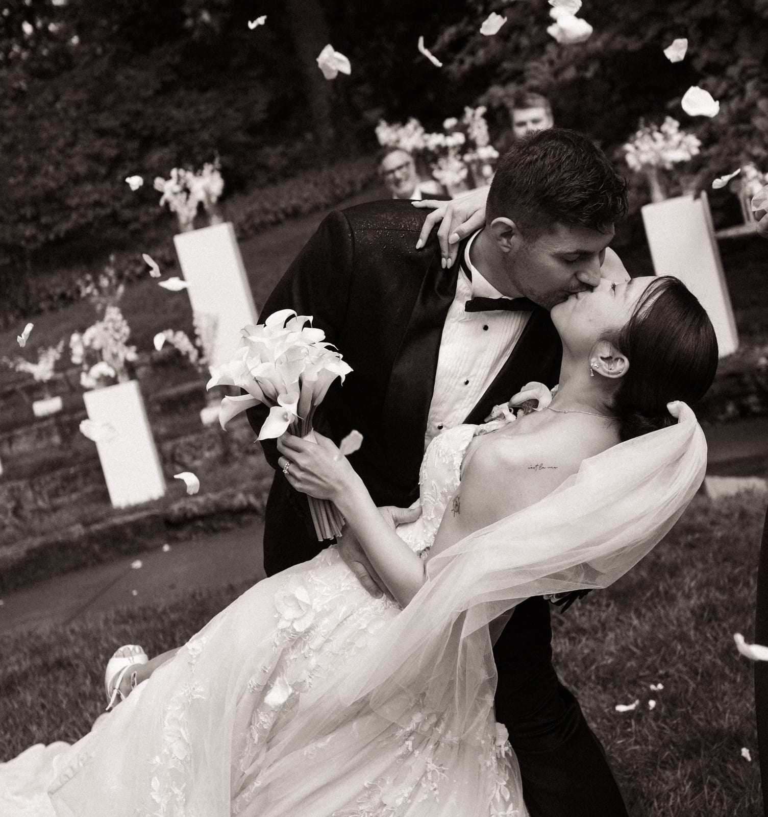 Sepia dip kiss with calla lily bouquet amid petal toss at the Sharon & Matt wedding — designed by Lael Florals