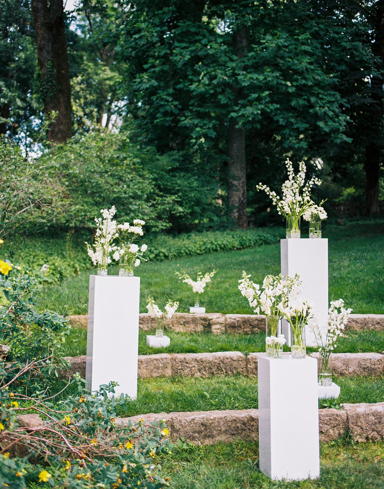 Tiered garden steps with white pedestal floral installation at the Sharon & Matt wedding — designed by Lael Florals